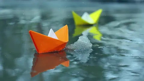 Paper boats drifting on quiet water.