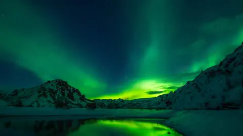 The northern lights rippling green above a dark ridgeline.